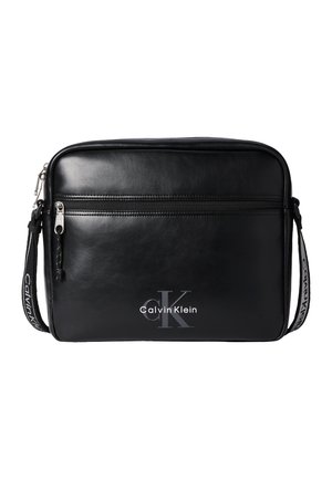 Μαύρη ορθογώνια τσάντα ώμου Calvin Klein με μπροστινή τσέπη με φερμουάρ και ρυθμιζόμενο λουρί με λογότυπο Calvin Klein.