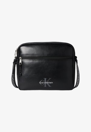 Sac à bandoulière rectangulaire noir Calvin Klein avec poche zippée à l'avant et sangle réglable portant le logo Calvin Klein.