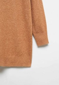 Manche et partie inférieure d'un pull tricoté marron clair avec poignets et ourlet côtelés sur fond blanc.