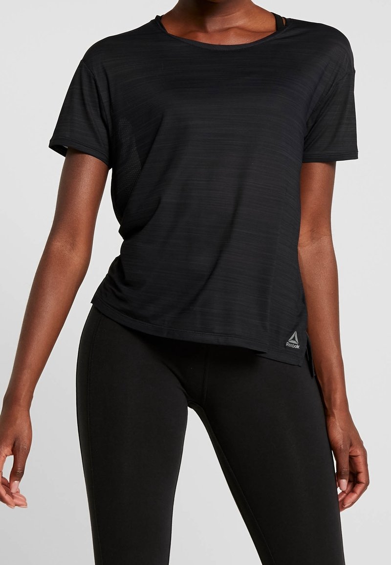 Black athletic t-shirt with a textured, striped pattern. Short sleeves, loose fit, side slits, and a small Reebok logo on the hem.