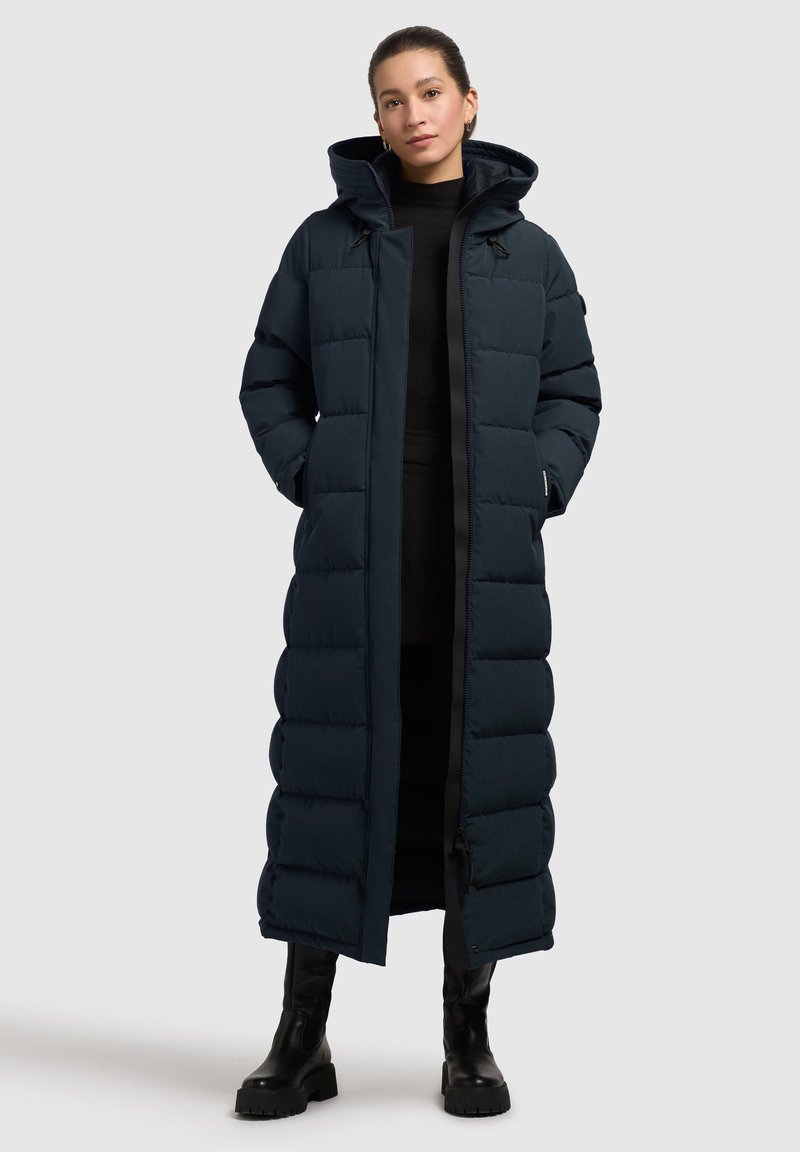 Abrigo acolchado largo en color azul marino con capucha, que presenta un diseño acolchado, cierre frontal con cremallera y bolsillos laterales. Tejido texturizado con un acabado suave.