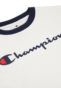 Camiseta de algodón blanca con cuello redondo azul marino y un destacado logo de "Champion" en azul marino con un acento rojo en el lado izquierdo.
