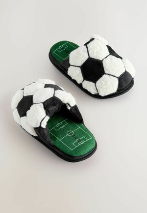 Svartvita fotbollstema tofflor med en plyschutsida, med en grön innersula utformad som en fotbollsplan.