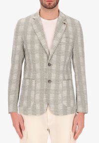 Blazer a quadri grigio chiaro con bottoni marroni, rever a scendere e tasche applicate. Realizzato in tessuto testurizzato, abbinato a una camicia bianca.
