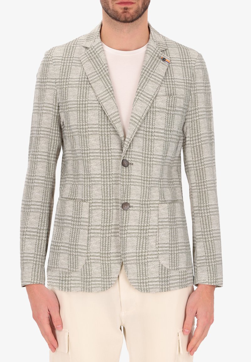 Blazer a quadri grigio chiaro con bottoni marroni, rever a scendere e tasche applicate. Realizzato in tessuto testurizzato, abbinato a una camicia bianca.