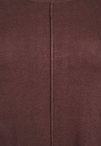 Close-up van bruin gebreide stof met een centrale verticale naad, met een fijne geribbelde textuur en gelijkmatige stiksels.