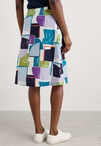 Una falda a la altura de la rodilla con un estampado geométrico multicolor en azul, verde, púrpura y negro, hecha de tejido ligero.