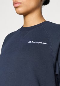 Μπλε σκούρο φούτερ με λαιμόκοψη crew, ριμπ μανσέτες και λογότυπο κεντημένο σε λευκό στο στήθος. Κατασκευασμένο από μαλακό υφασμάτινο υλικό.