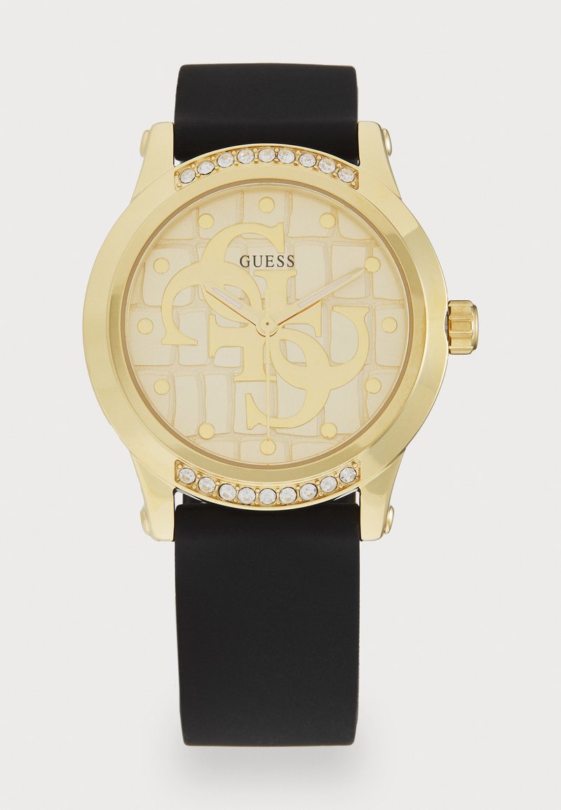 Ronde gouden Guess-horloge met heldere kristallen op de lunette, beige wijzerplaat met patroon en logo, gouden wijzers en zwarte siliconen band.