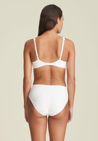 Biały kostium kąpielowy w kratkę z fakturowanego materiału; góra ma regulowane ramiączka i falbanowy brzeg, a dół jest w stylu wysokiej talii.
