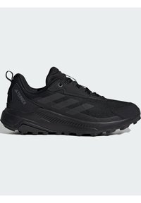 Chaussures de trail running noires avec une tige en mesh respirant, des superpositions texturées, un talon renforcé et une semelle en caoutchouc agressive pour une meilleure traction.