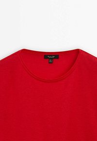 Maglietta rossa a maniche corte con scollo rotondo, realizzata in tessuto morbido, con dettagli di cucitura visibili e un'etichetta della taglia all'interno del colletto.