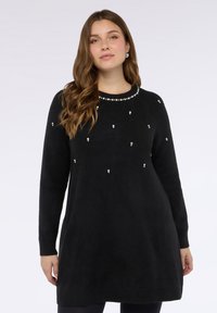 Schwarzes Pulloverkleid mit abgerundetem Ausschnitt, verziert mit kleinen weißen Perlen, langen Ärmeln und einem gerippten Saum für Struktur.