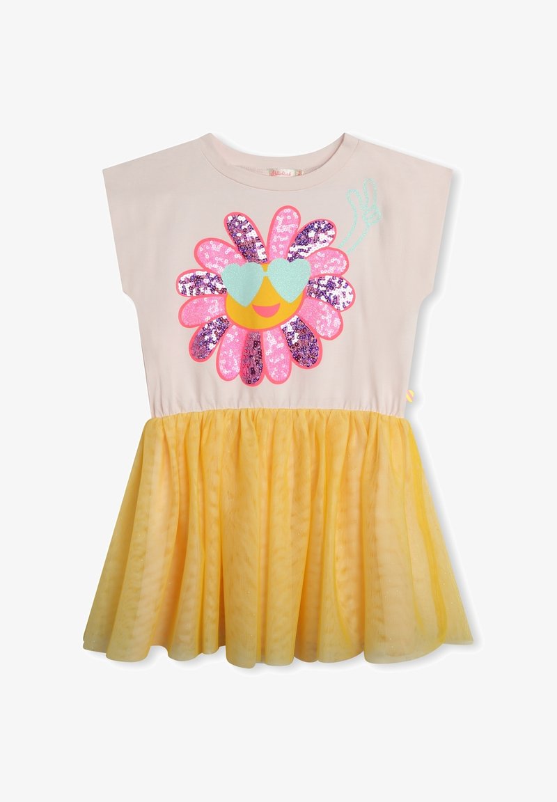 Robe beige avec jupe en tulle jaune, ornée d'une fleur pailletée avec des lunettes de soleil en forme de cœur et un signe de paix sur la poitrine.