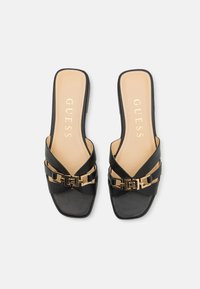 Infradito nere con più strap incrociati, punta quadrata, dettagli in hardware color oro e soletta beige con il nome del marchio.