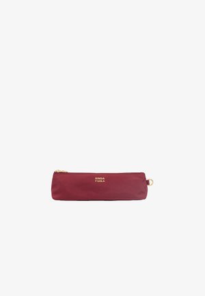 Trousse bordeaux in una texture liscia, con una cerniera dorata e un accento del logo. Forma cilindrica, design compatto.