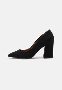 Schwarze Wildleder-Pumps mit hohem Absatz, spitz zulaufender Vorderseite und Blockabsatz, die über eine glatte Textur und ein schlichtes Design verfügen, geeignet für formelle Anlässe.