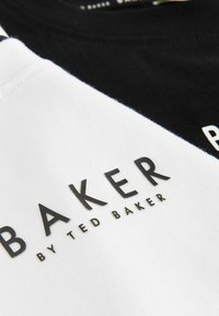 Juodos ir baltos trumpomis rankovėmis marškinėliai su tekstu "BAKER" ir "by TED BAKER" ryškiai, tekstūruotais juodais rašmenimis. Pagaminta iš medvilnės mišinio.