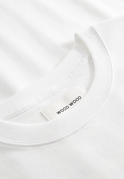 Hvit bomulls-T-skjorte med rund hals og flat søm. Merket viser "WOOD WOOD." Myk tekstur med jevn finish.
