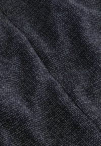 Tela tejida de color azul oscuro con un patrón apretado y textura, que presenta hilos de colores claros que crean profundidad e interés visual.