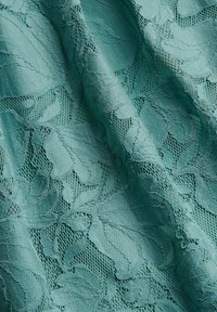 Tela de encaje en color teal con un patrón floral, detalles texturizados y una superficie general suave. Apariencia ligera y delicada.