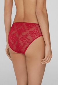 Red lace high-waisted underwear with floral pattern and sheer mesh detailing. Features a smooth, elastic waistband.