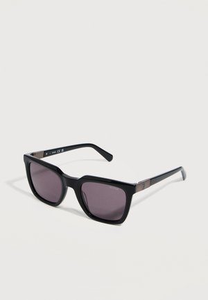 Black rectangular sunglasses with dark lenses and subtle metallic accents on the temples, resting on a white surface.