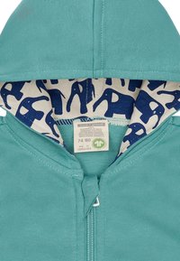 Felpa con zip turchese con fodera navale a motivo di elefanti. Realizzata in cotone biologico, include un'etichetta con taglia e istruzioni per la cura.