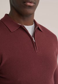 Bordo polo majica s patentnim zatvaračem i teksturiranim pletenim uzorkom, s ovratnikom i slojevito ispod sive majice.