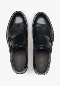 Czarne skórzane buty o teksturowanym wykończeniu, z detalami w stylu brogue i podwójnymi klamrami po bokach. Gładki i wypolerowany przód.