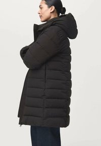 Zwarte pufferjack met een capuchon, met een gequilte uitstraling, ritssluiting en een middellange pasvorm. Gemaakt van geïsoleerd materiaal voor warmte.