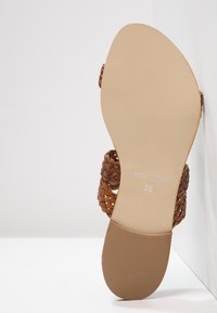 Sandalo in pelle intrecciata marrone con suola piatta, che mostra un fondo beige liscio e dettagli stampati: "MADE IN ITALY" e taglia "39."
