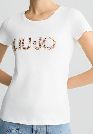 Femme portant un t-shirt blanc ajusté à manches courtes avec l'inscription « LIU·JO » en imprimé léopard sur la poitrine.