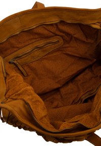 Innenraum einer tanfarbenen Lederhandtasche mit strukturiertem Finish. Verfügt über eine Reißverschlusstasche und ein geräumiges Hauptfach. Weicher, leicht matter Stoff.
