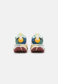 Zapatillas multicolores con una parte superior de malla transpirable, que presentan un diseño en azul y verde, acentos amarillos y una suela gruesa color marrón.