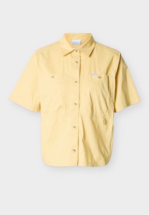 Īsām piedurknēm gaiši dzeltena pogājama kreklas ar divām priekšējām kabatām, apkakli un mazu auduma cilpu uz labās kabatas.