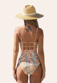 Crèmekleurige badpak met bloemenprint in oranje en groen. Heeft dunne schouderbandjes en een uniek rugontwerp met uitsnijdingen.