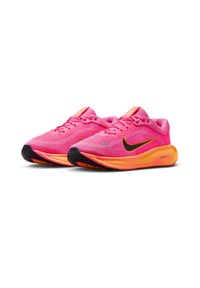 Rozā sporta apavi ar elpojošu auduma augšdaļu, ar melnu Nike swoosh, košām dzeltenām akcentiem un komfortablu zole dizainu.