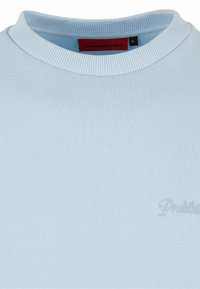 Hellblaues Baumwoll-Sweatshirt mit Rundhalsausschnitt, geripptem Kragen und dezentem, ton-in-ton gesticktem "Prohibited"-Text. Größenetikett im Inneren sichtbar.