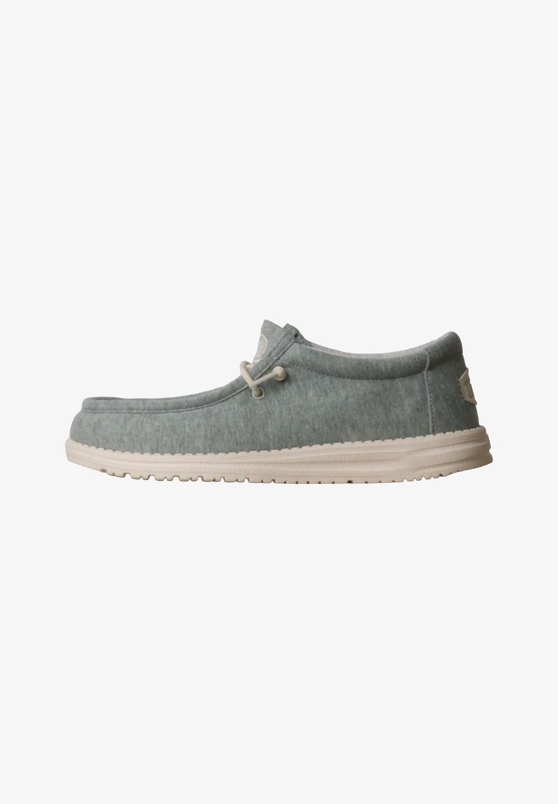 Chaussure décontractée à enfiler en tissu gris clair avec semelle blanche et lacets blancs, conçue pour le confort et le port quotidien.