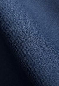 Donker marineblauw stof met een gladde, gestructureerde weving. Het materiaal lijkt zacht, met een consistent patroon en een subtiele glans.