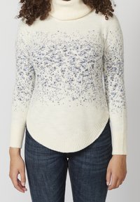 Maglione a collo alto color crema con un motivo blu variegato, polsini e orlo a costine, schiena leggermente più lunga e tessuto morbido e strutturato.