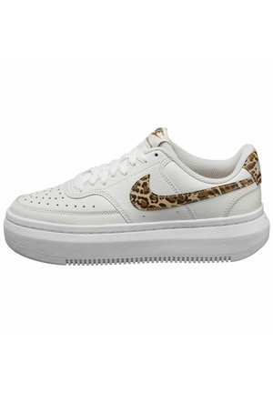 Baskets blanches avec semelle épaisse, embout perforé, et détail du logo Nike en imprimé léopard sur le côté et au talon, vues de profil.