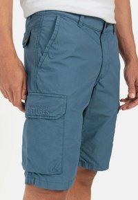 Lysblå cargo shorts lavet af tekstureret stof, har flere lommer og inkluderer subtil branding på siden.