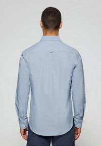Light blue long-sleeve shirt with a classic collar, straight hem, and buttoned cuffs. Smooth texture with a back yoke detail.