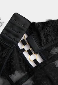 Černé krajkové prádlo s texturovaným páskem, zlatými kroužky a nastavitelným háčkovým uzávěrem pro bezpečné uchycení.