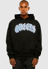 Sort hættetrøje med stor, blå, stiliseret tekst "QUEENS." Har en frontlomme og snoretræk til hætten. Stoffet ser glat og tykt ud.