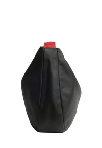 Borsa in tessuto nero testurizzato con un manico superiore rosso in contrasto, caratterizzata da una forma arrotondata e un design senza cuciture, ideale per un uso casual.