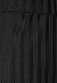 Černá plisovaná tkanina s vertikálními ribbovanými pruhy, ukazující texturovaný povrch s alternativními matnými a lesklými sekcemi.