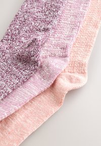 Twee paar gebreide sokken: één in een paars met roze tint en witte spikkels, en het andere in een lichtere roze kleur met een subtiele textuur.